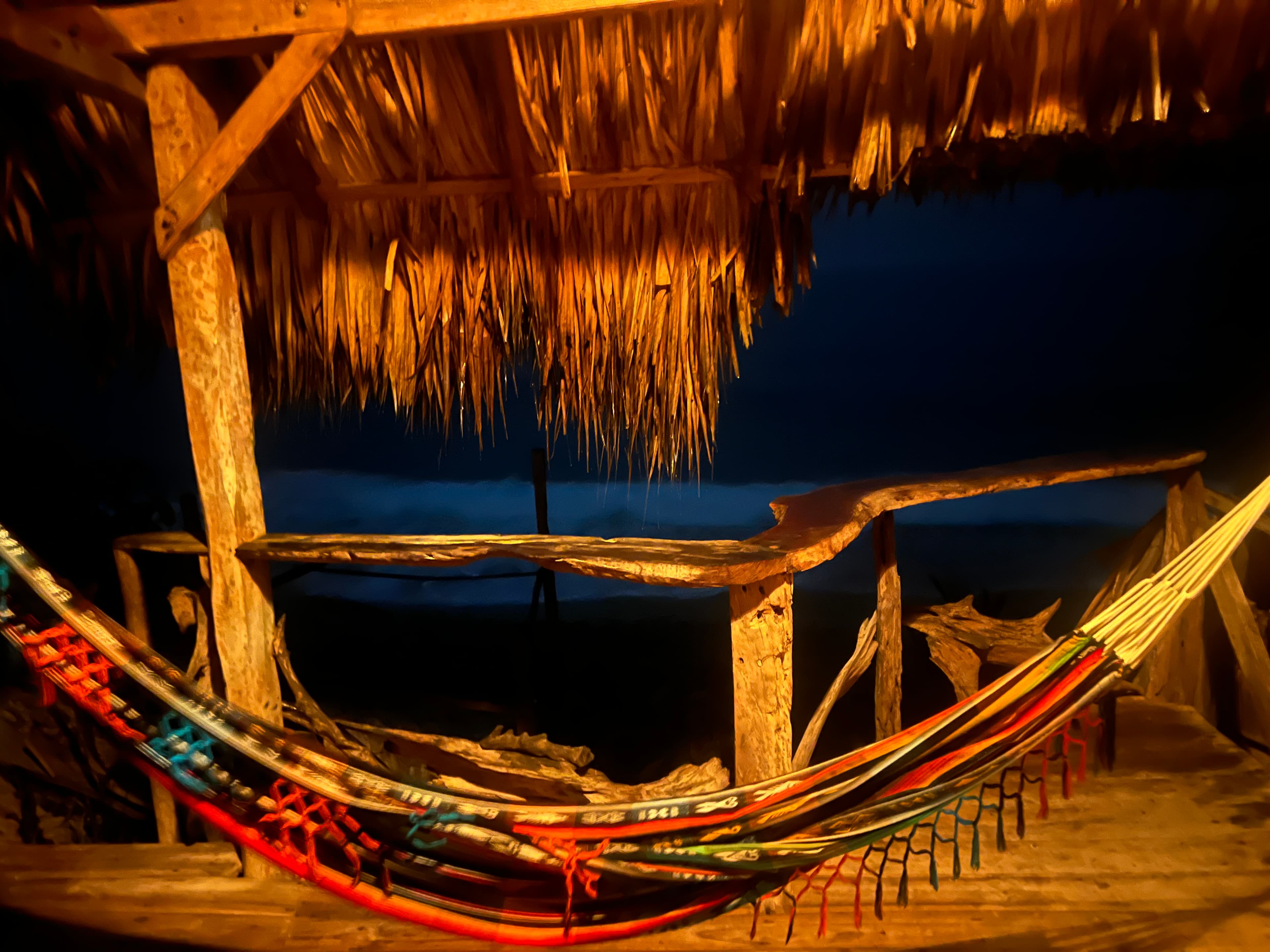 Hammocks under a thatched roof at dusk in Santa Marta
